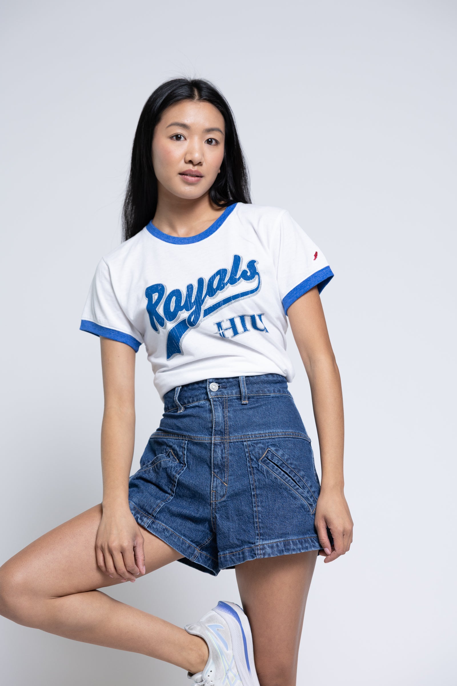 Woman wearing a 'Royals' t-shirt and denim shorts on a white background
